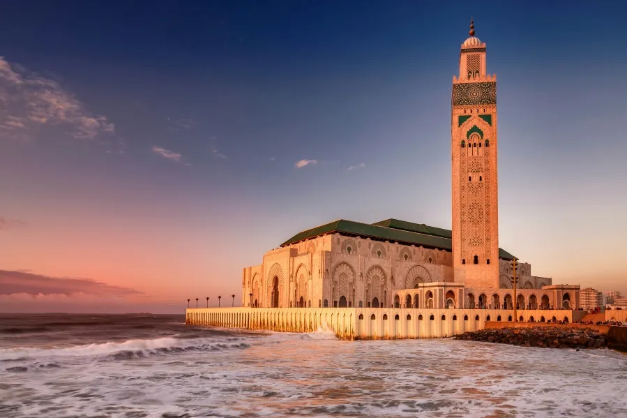 The stunning mosque of Casablanca, Morocco, illuminated by the warm hues of sunset, showcasing its architectural beauty.